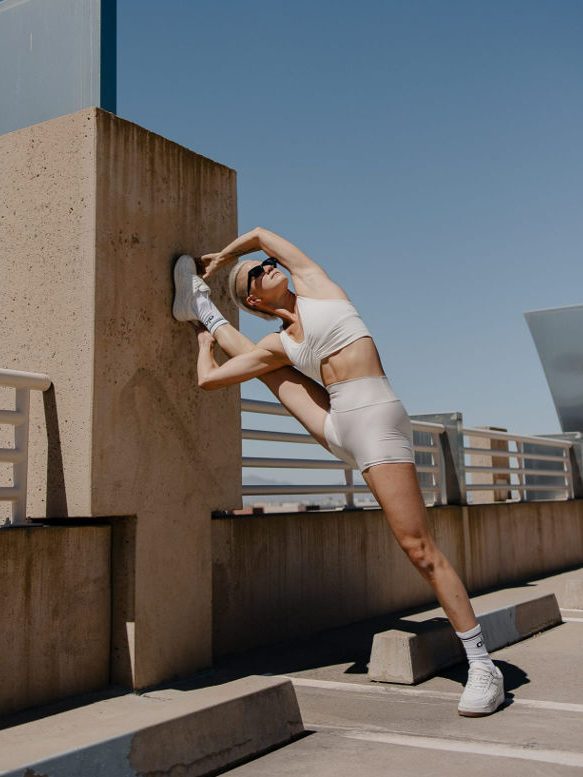 girl stretching outside in white alo yoga brand clothes 