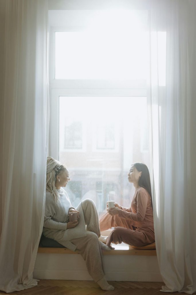 two women embracing demure aesthetics enjoying a cup of coffee