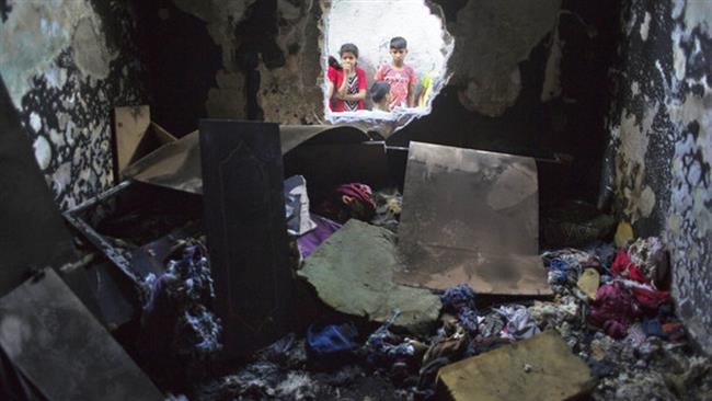 Palestinian children look through a hole in a wall at a burned bedroom where three children were killed by candle sparked on their family house in the Shati refugee camp in Gaza City, Saturday, May 7, 2016. Source: PressTV.