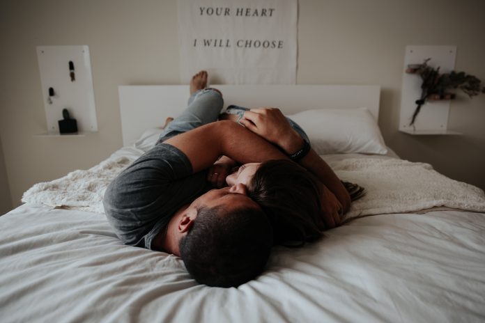 Couple lying on bed facing each other