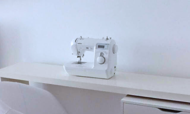 Een naaimachine op een witte tafel.