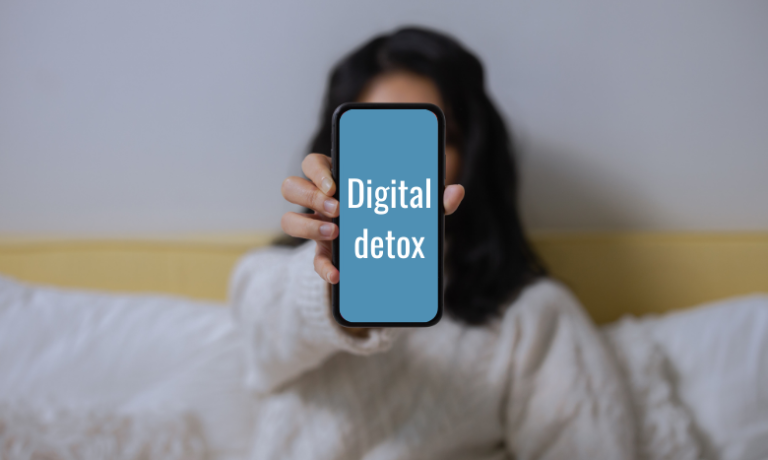 Een dame houdt een smartphone vast waar Digital Detox op staat.