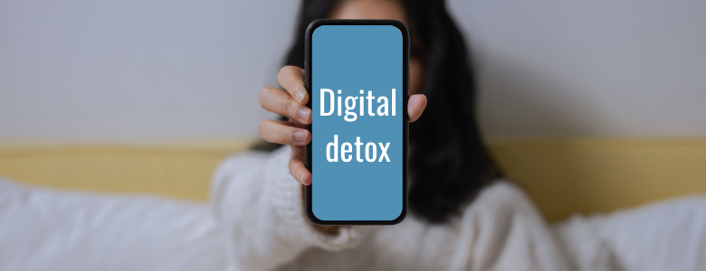 Een dame houdt een smartphone vast waar Digital Detox op staat.