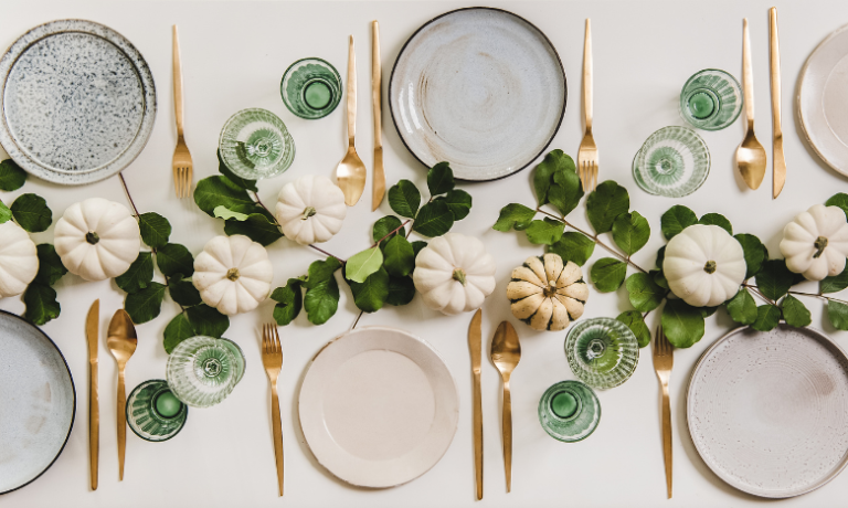 Een gedekte tafel met borden, bestek en natuurproducten als versiering.