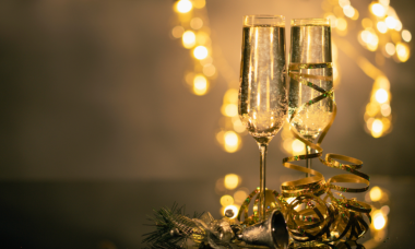 Twee glazen champagne tegen een feestelijke achtergrond.