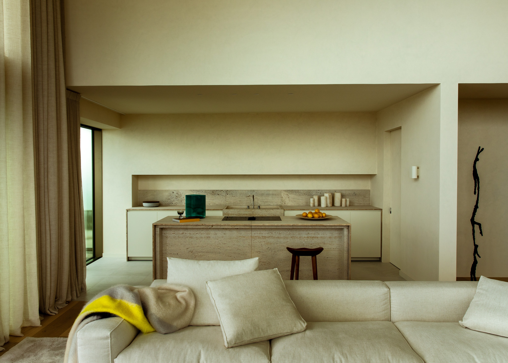 Living met sofa en open keukenwand in zachte beige tinten.