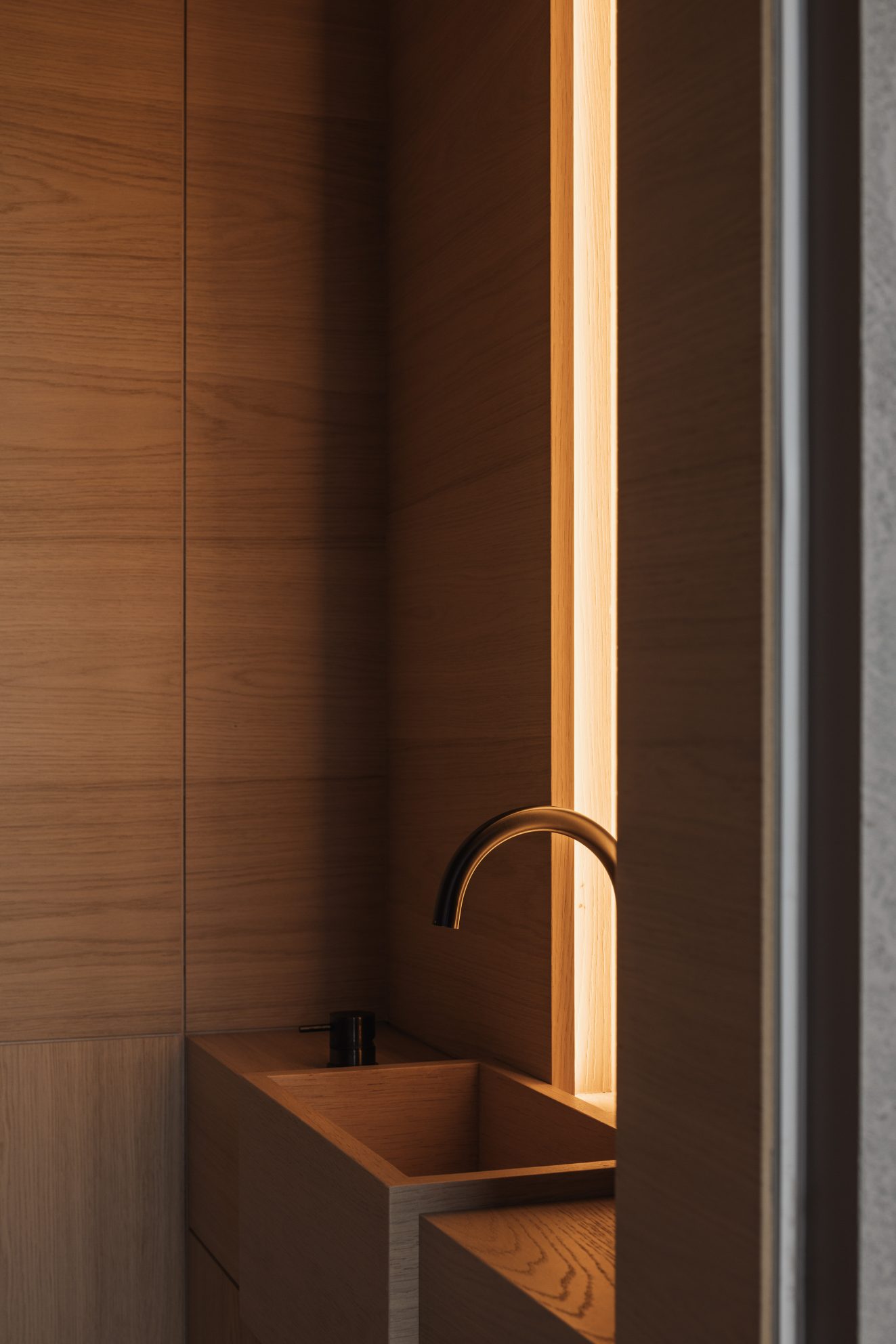 Houten wastafel met smalle verticale lichtstrook ernaast