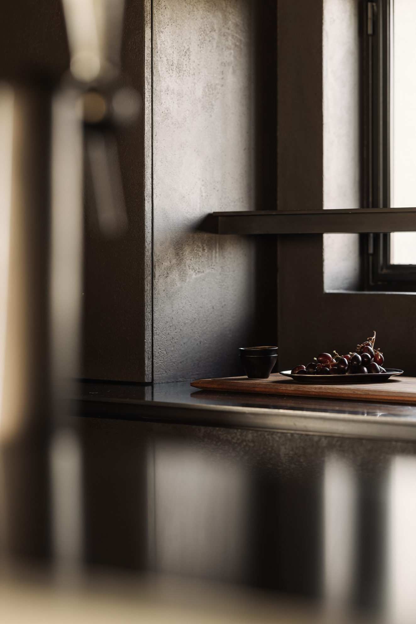 Druiven op houten plank in een donkere keukenhoek met licht langs het raam