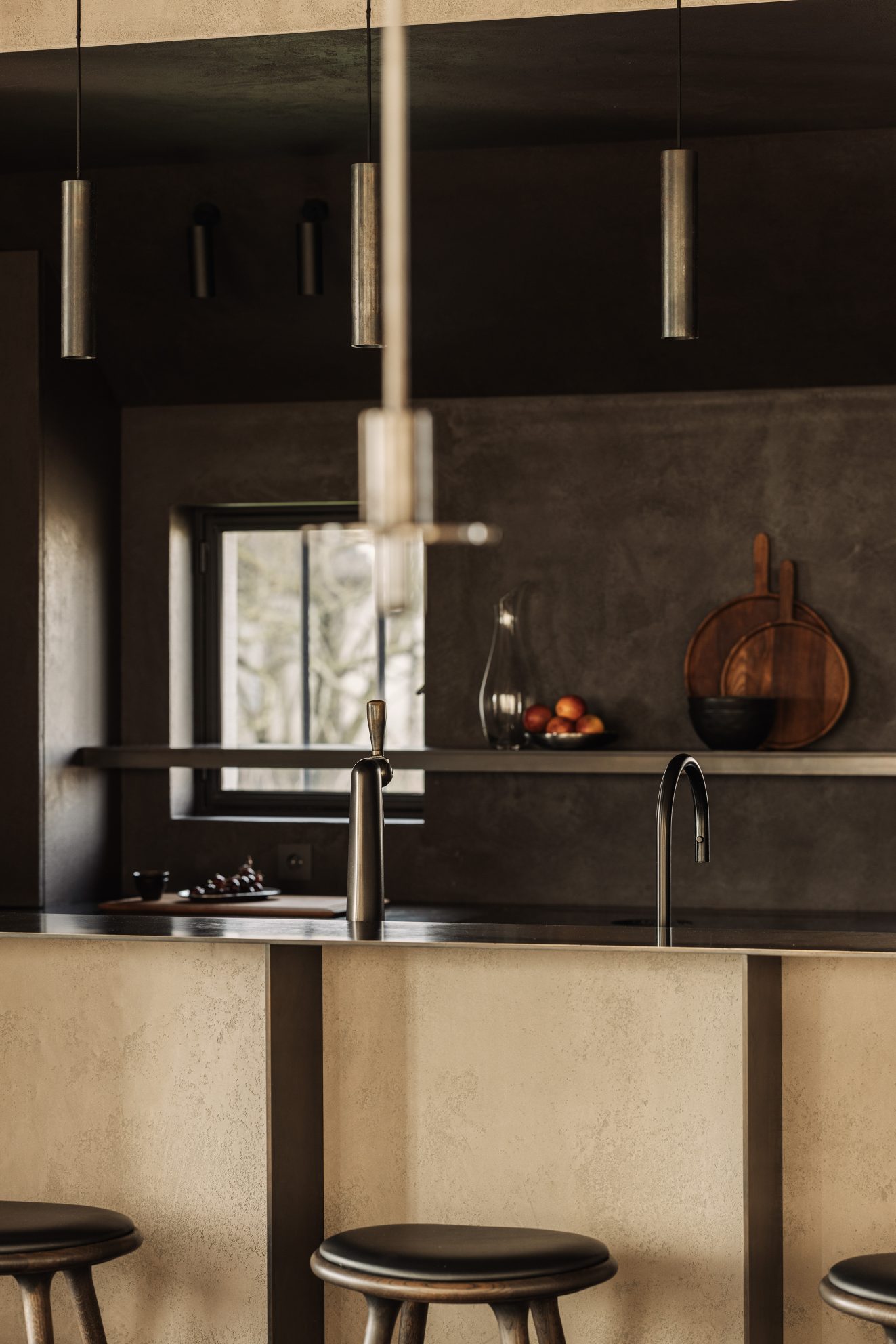 Keuken met strakke bar, pendellampen en twee ramen in donkere wand