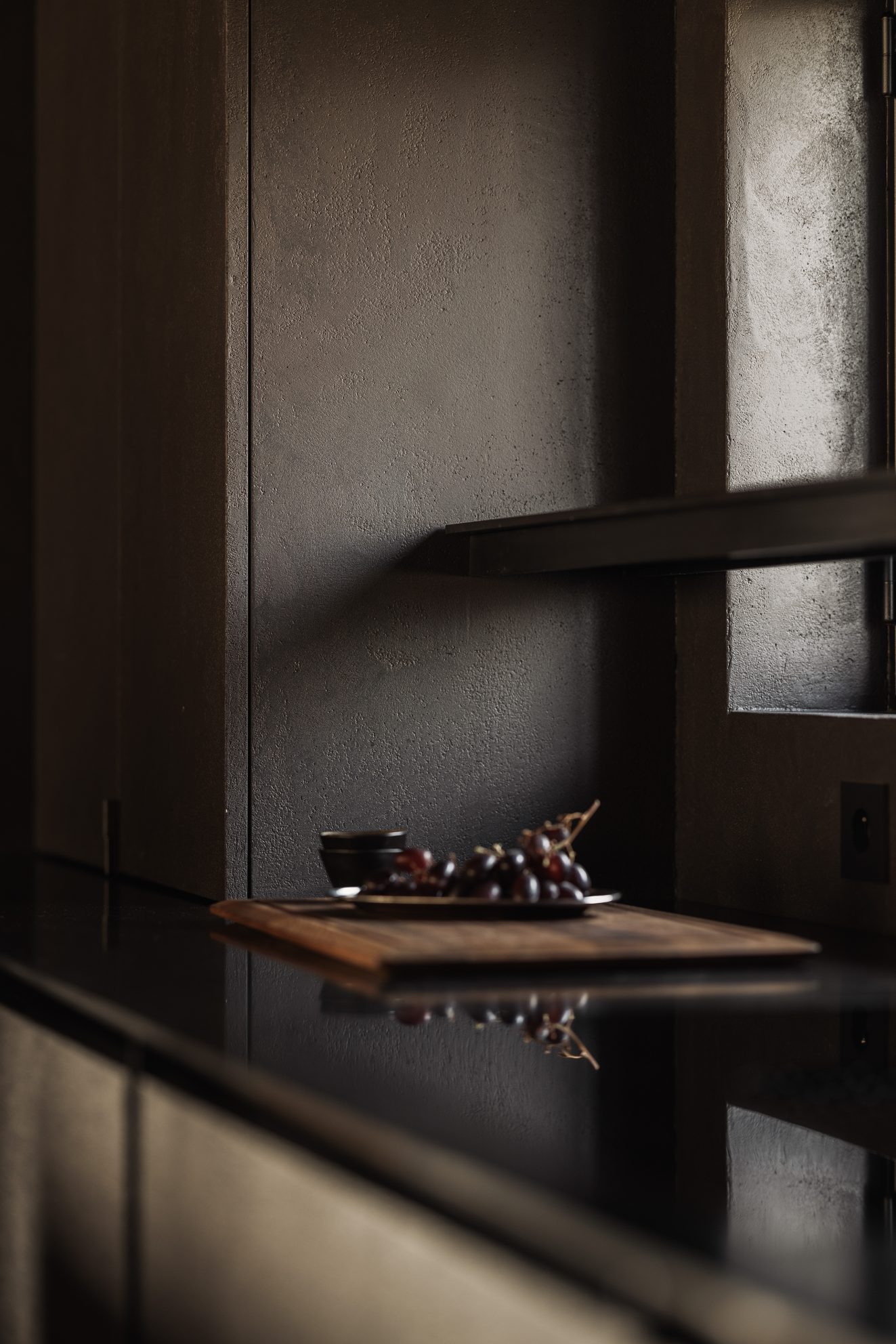 Druiven op een houten plank tegen een donkere keukenwand