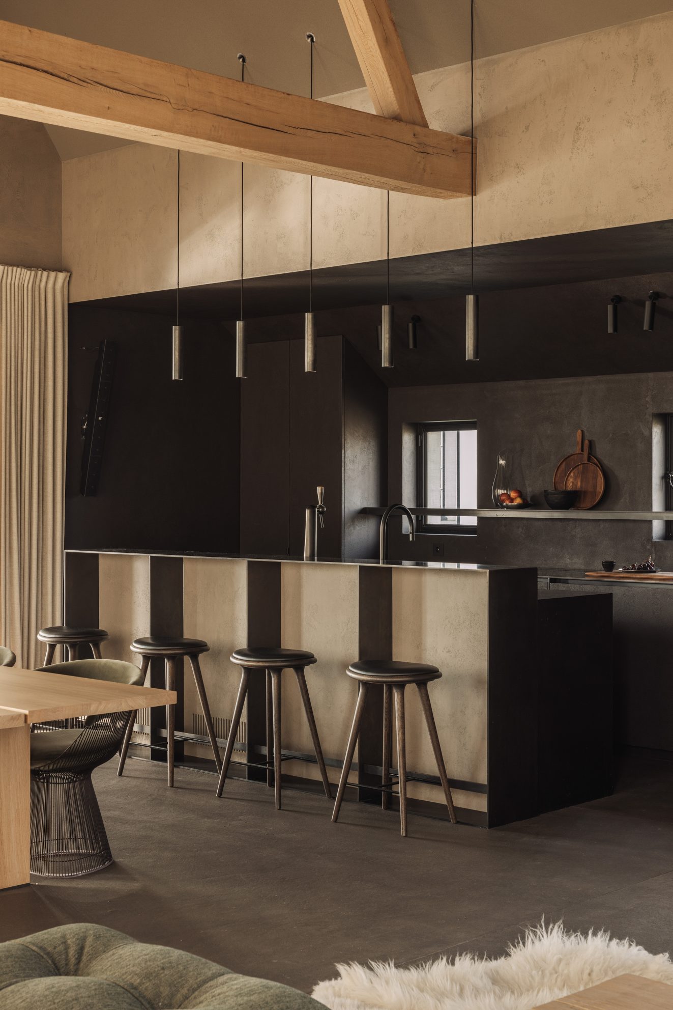 Keukenbar met donkere kastenwand en drie hoge krukken