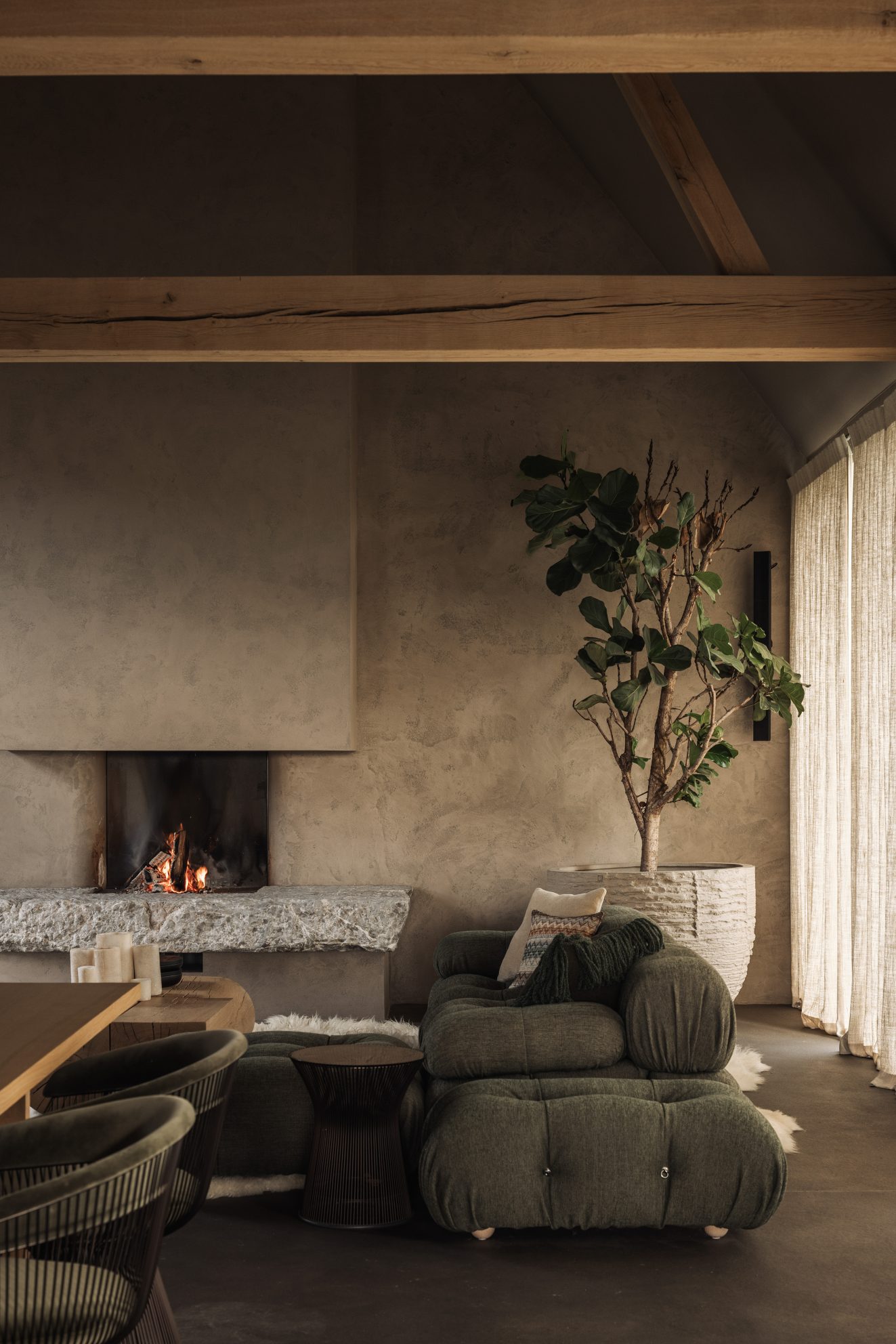 Leefruimte met open haard, groene loungezetel en grote kamerplant