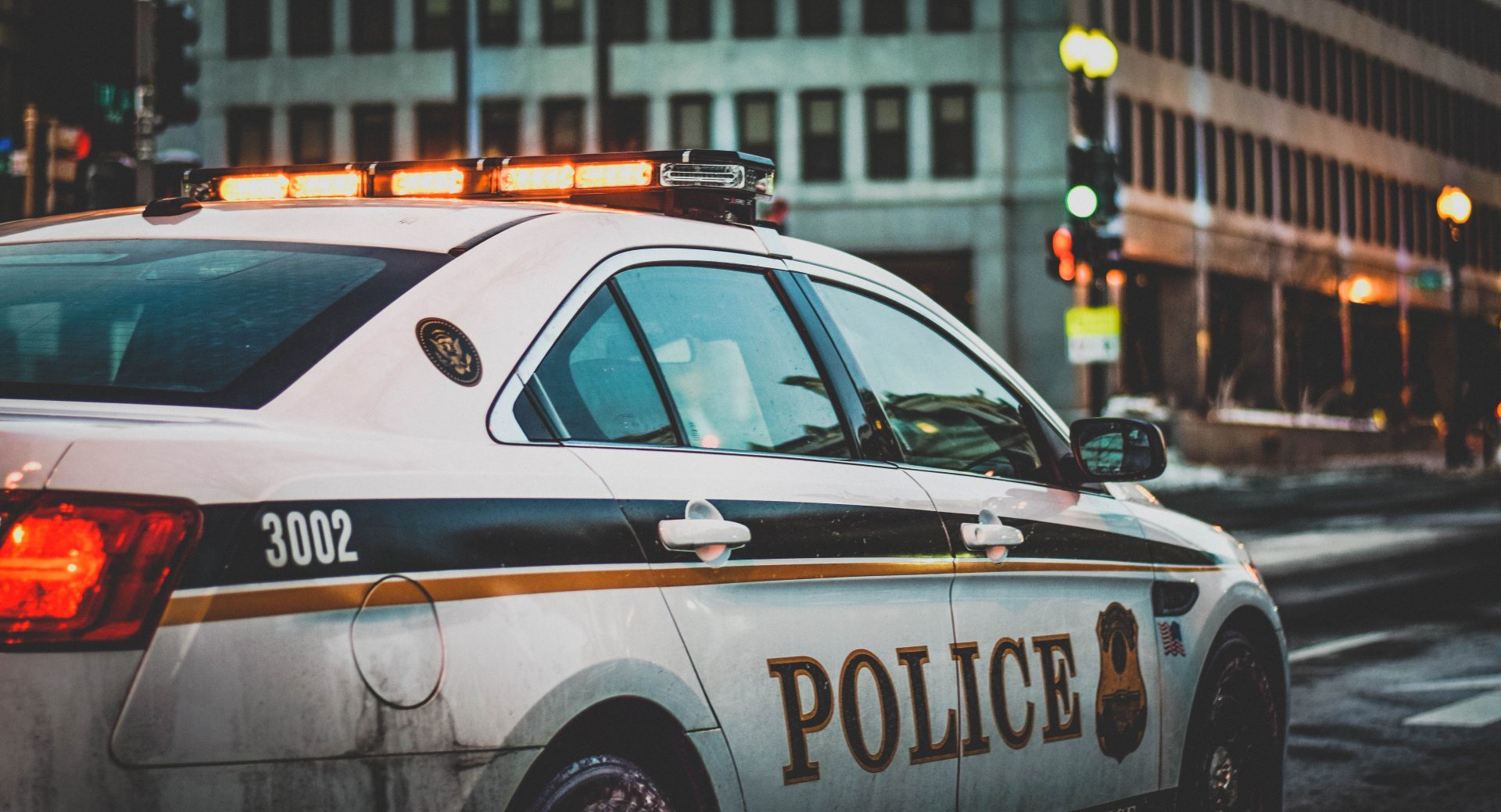 An American police car driving down a street in an urban area