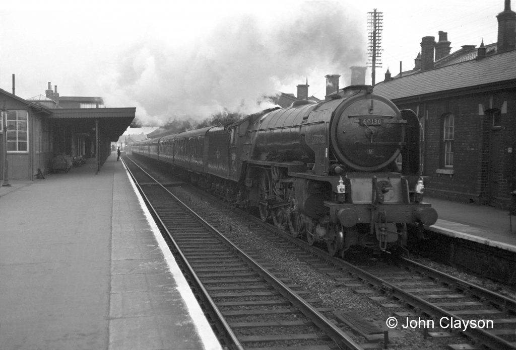A southbound express passenger train speeds through the station on 25th May 1962, hauled by class A1 locomotive No.60130 Kestrel of Copley Hill shed (56C) in Leeds. This is the point at which Alan's driver would prepare to 'drop the lever', a saying going back to Victorian times when all locomotives had a large vertical lever which worked in a notched quadrant on the driver's side of the cab. The driver would 'drop' the lever down, or forward, by a notch or two to increase power and maintain speed up a gradient. From around the 1900s the lever was replaced by a rotating handle on most locomotives, except those intended for low powered freight and shunting work. This explains why Alan says '...drop the lever down half a turn or more...'. Photograph by Cedric A. Clayson