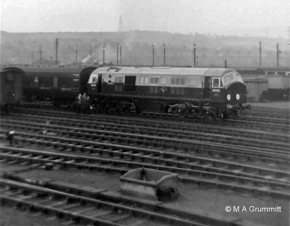 Progressing away from the camera this view from the Yard Box shows: o the spur into the dock at the end of the Down platform o the Down Slow line (partly obscured by the concrete bunker) o the north end of carriage sidings 2, 3, 4 and 5 (some stored roling stock being visible on the left) o the Up and Down Goods line (not signalled by the Yard Box), on which the train is standing. The locomotive is brand new Type 2 diesel electric No. D6122 on a trial run from Doncaster to Grantham. Mick Gummitt tells us "It had just run round its train of empty stock ready to go back to Doncaster - hence all the attention by the inspectors." These locomotives didn't normally operate in the Grantham area. D6122 went into service at Ipswich in the second half of 1959, soon after this trial trip. They were not the most reliable machines. All 38 initially sent south (to Hornsey, Stratford and Ipswich) returned to Scotland during 1960 to see out their relatively short service lives. Photograph by Mick Grummitt.