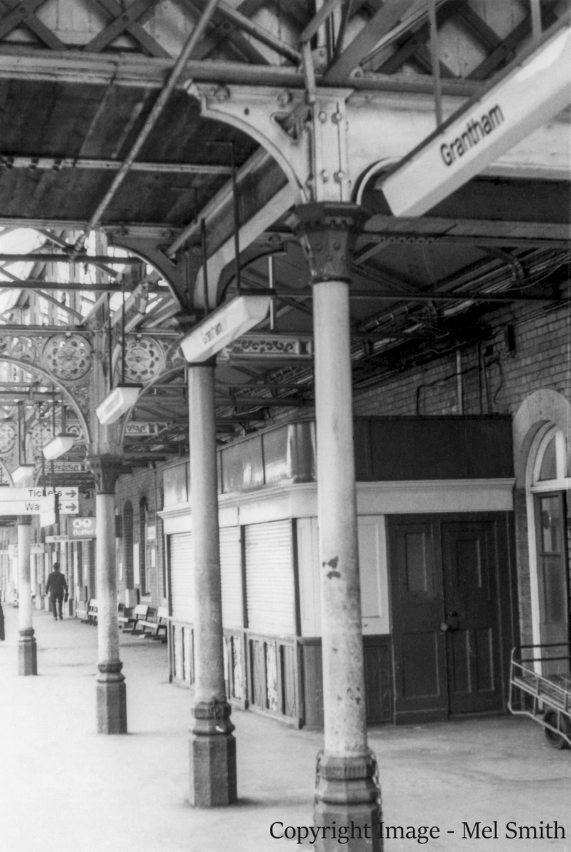 Moving along past the Book Stall we pause to glance upwards, taking in the fine roof detail and part of the underside of the footbridge. The chains on the columns were used to secure trolleys. Copyright Image - Mel Smith