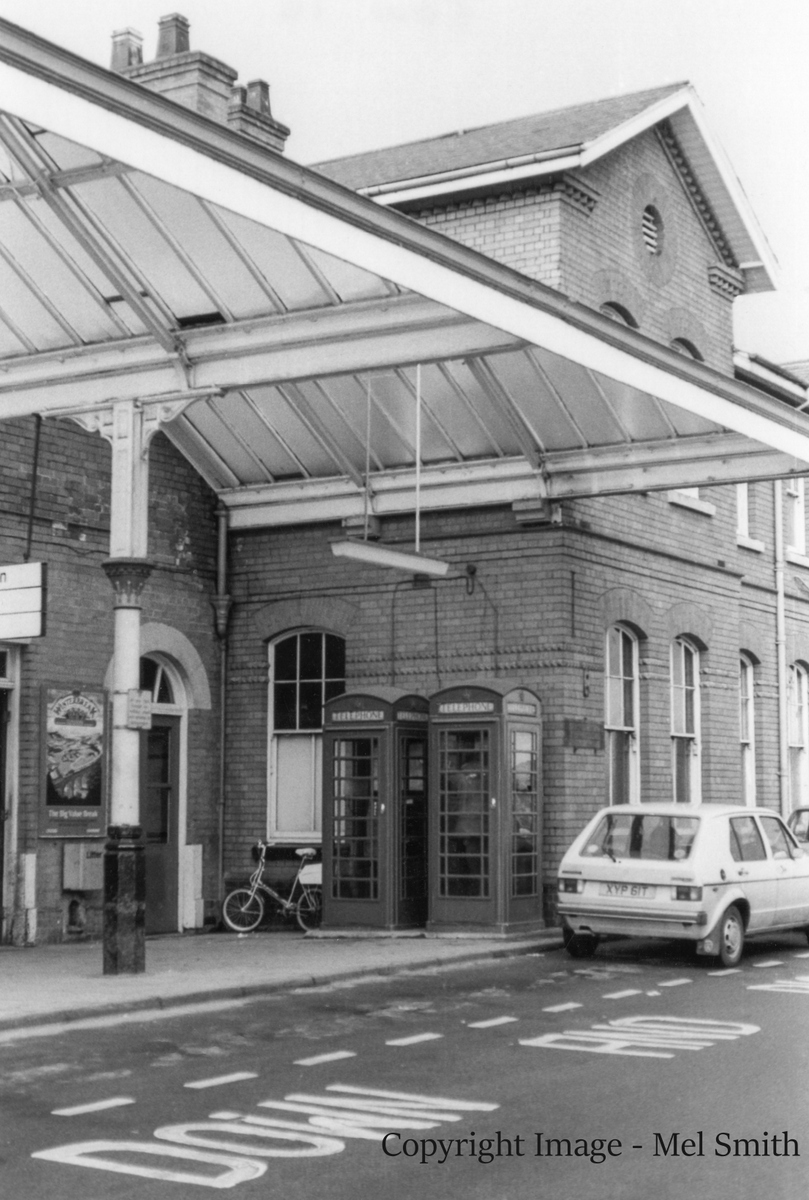 Two red telephone boxes stand guard outside the main entrance. Note the "Shopper" bike adjacent. Copyright Image - Mel Smith