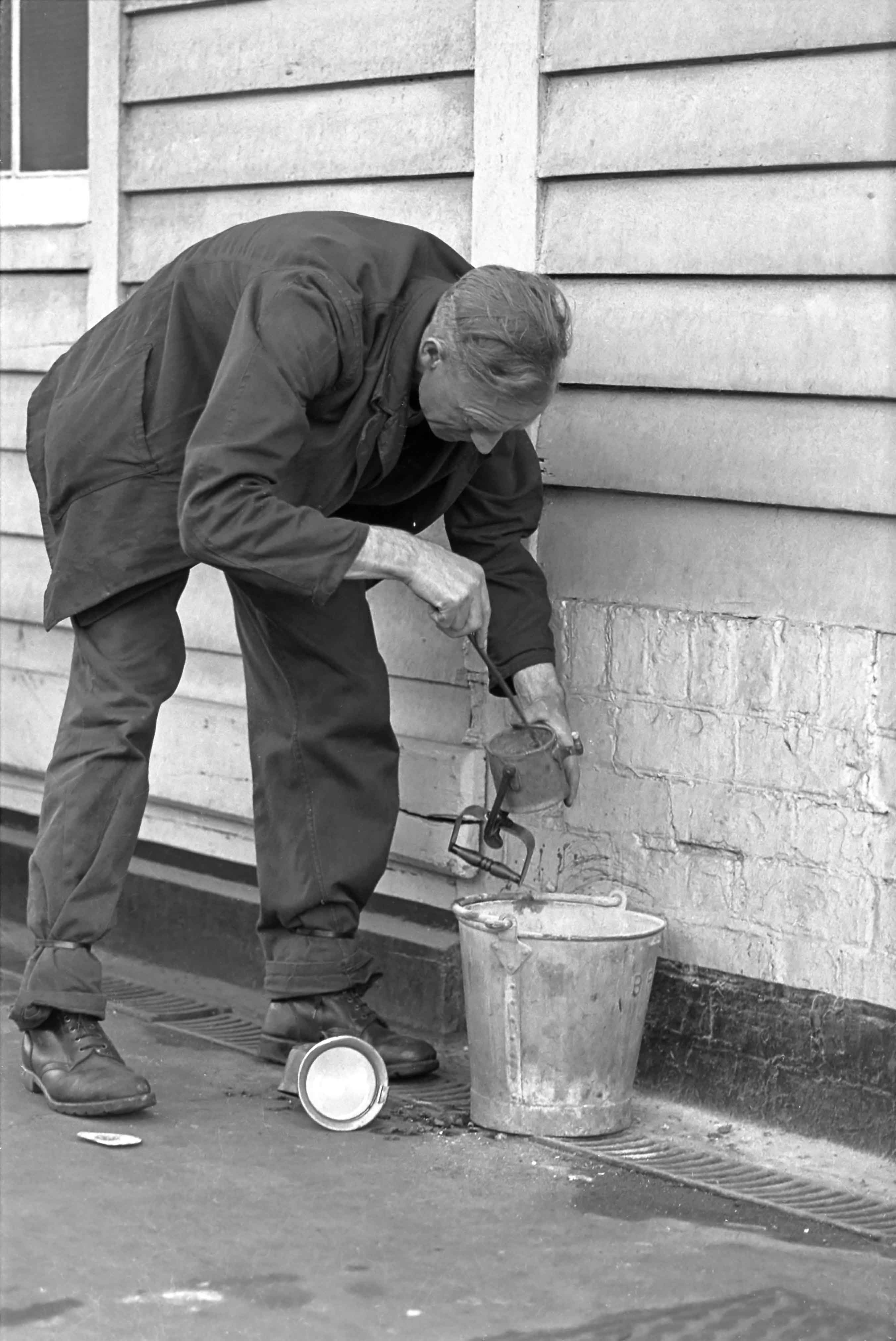 This is Joe Chappell, one of the Carriage & Wagon Examiners, cleaning out a carbide lamp. This type of lamp burns acetylene gas, which is generated internally from water and a chemical called calcium carbide. The acetylene gave an intense white light by which the examiners could see to do their work at night. Photograph by Cedric A. Clayson, © John Clayson