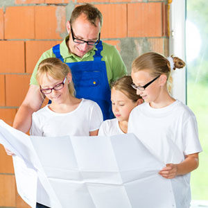 man and three girls reading paper