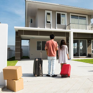 man and woman with bag in front of house