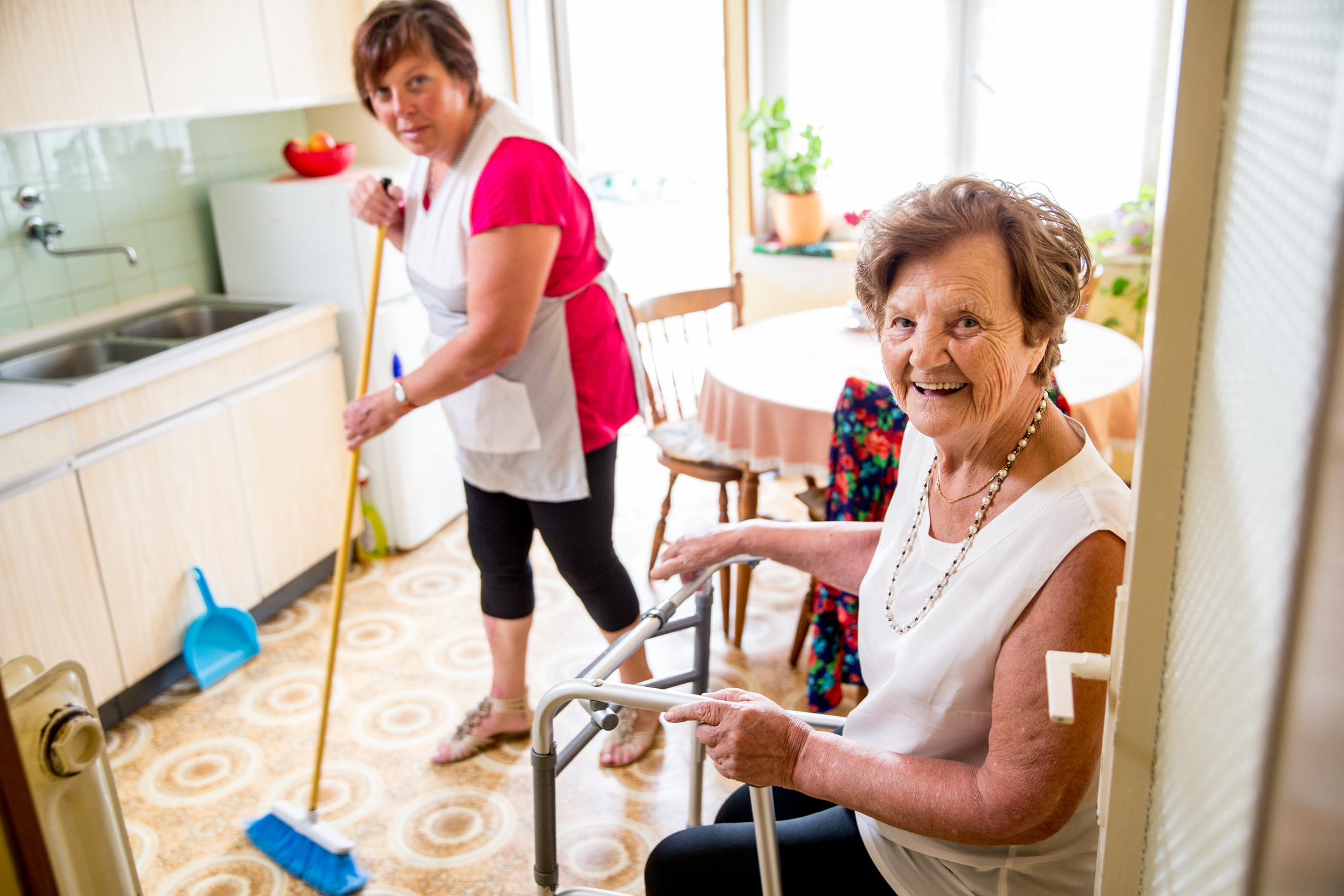 Elderly Woman talking with a caregiver while she is doing chores