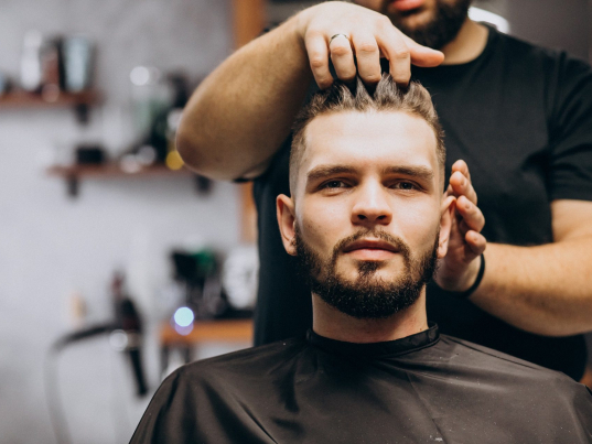 Hairdresser at a barber shop styling hair of a client