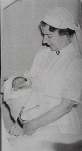 Jordmor Kristine Stang med nyfødt barn. Ukjent fotograf.