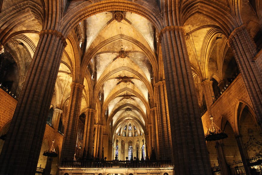 Den välvda gotiska interiören av La Catedral i Barcelona, ​​ett brett, skyhögt utrymme uppdelat i ett centralt långhus och två gångar med rader av eleganta, smala pelare