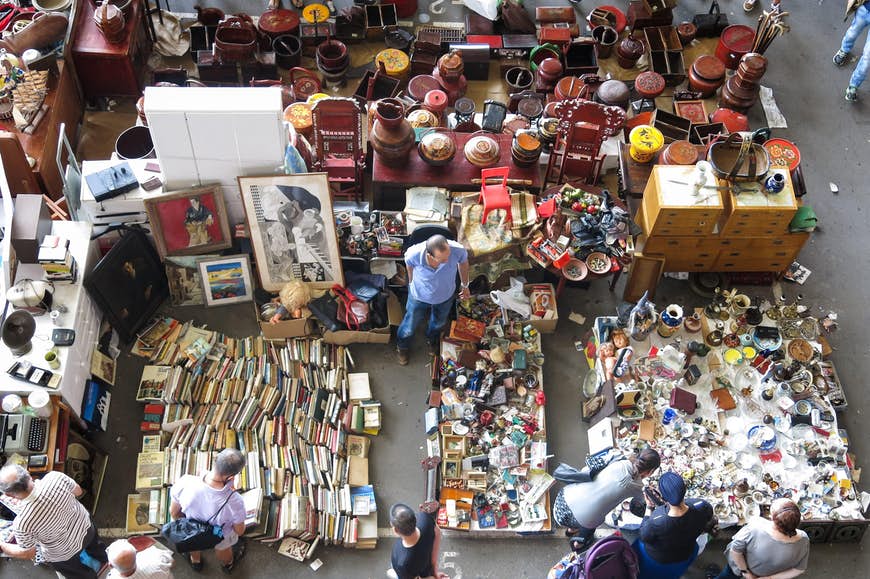 En bild ovanifrån av bord, avsatser och golvytor helt täckta av föremål till salu, inklusive böcker, korgar, elektronik, vaser och prydnadssaker.