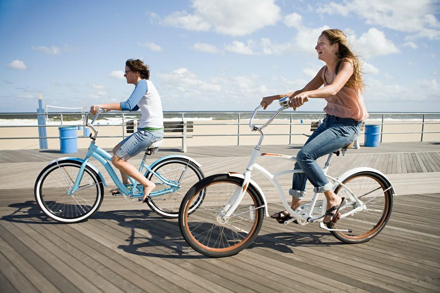 Två kvinnor som cyklar på strandpromenaden