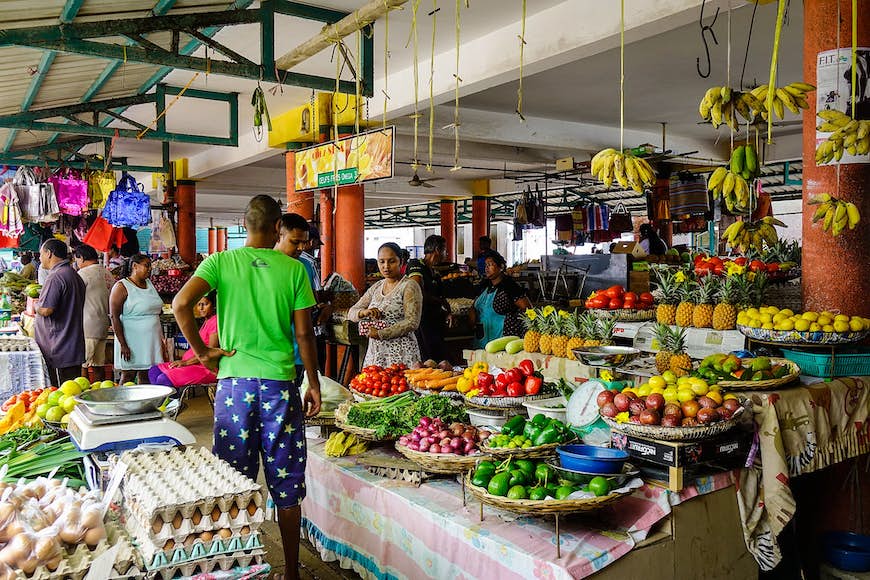 En marknad på Mauritius, med människor vid ett stånd lastat med färgglada färskvaror.