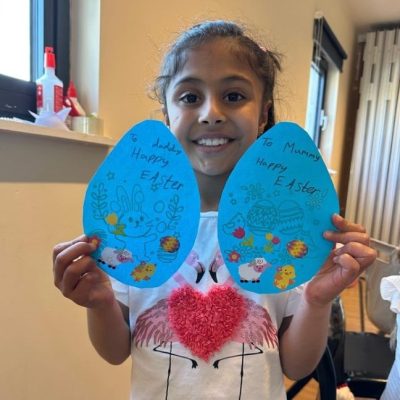 Photograph of girl with the 2 blue Easter eggs with Easter messages to mum and dad.