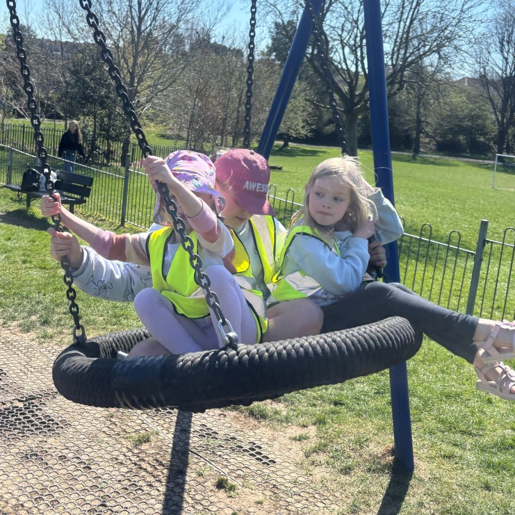 Photo of 3 girls enjoying a swing in the playground.