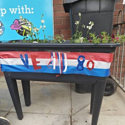 Photo of the VE Day planter. Full of red, white and blue flowers. And red, white and blue ribbon to decorate it.