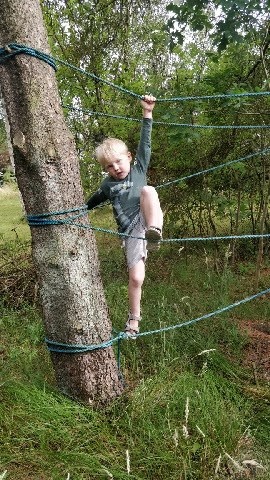 Moritz som klatrer på reb bundet til træerne.