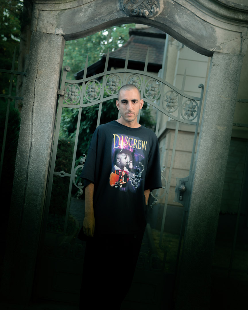 A man standing in front of a wrought iron gate.