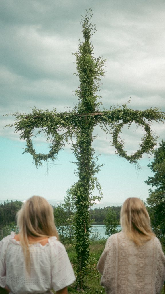 Midsummer tree with two girls standing beneath it.