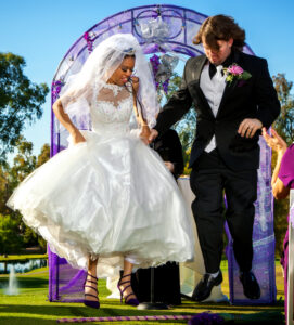 A bride and groom jump the broom in their wedding ceremony.