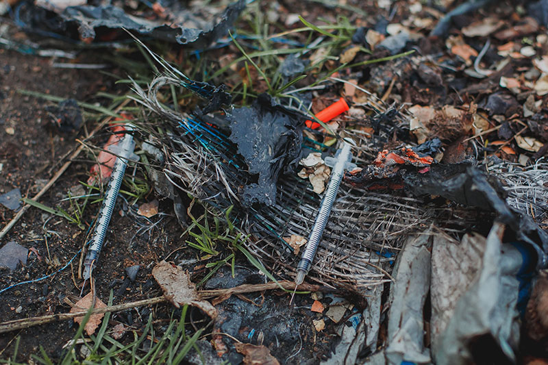 Used needles laying on wet ground