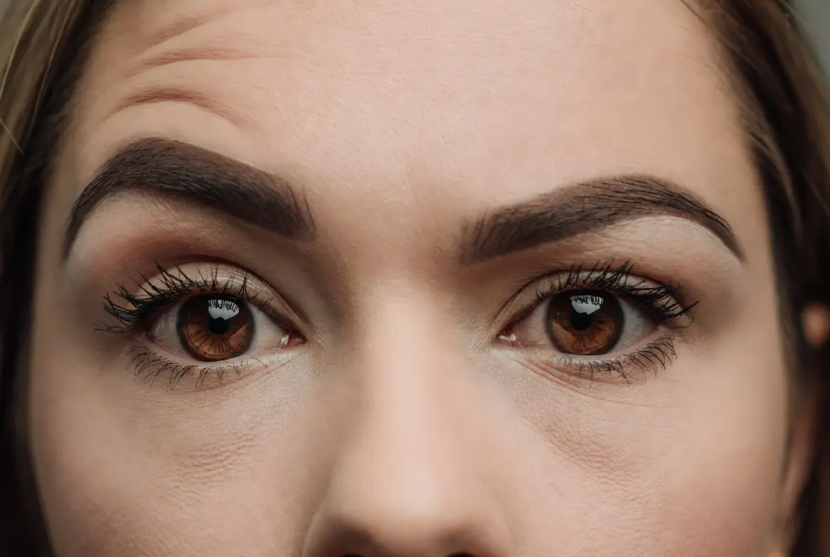 Close-up photo of a woman raising her eyebrows with visible forehead lines, showing a clear raised-eyebrow expression.