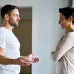 Open vs closed body language illustrated with one person showing open posture and another showing closed posture in a neutral social setting.