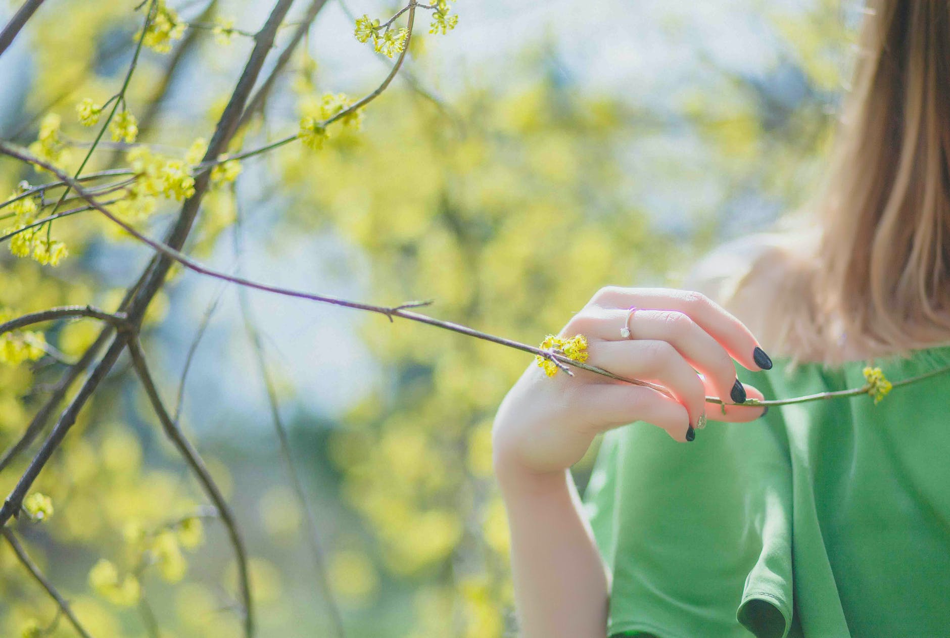 closeup photography of woman wearing green top holding leaf