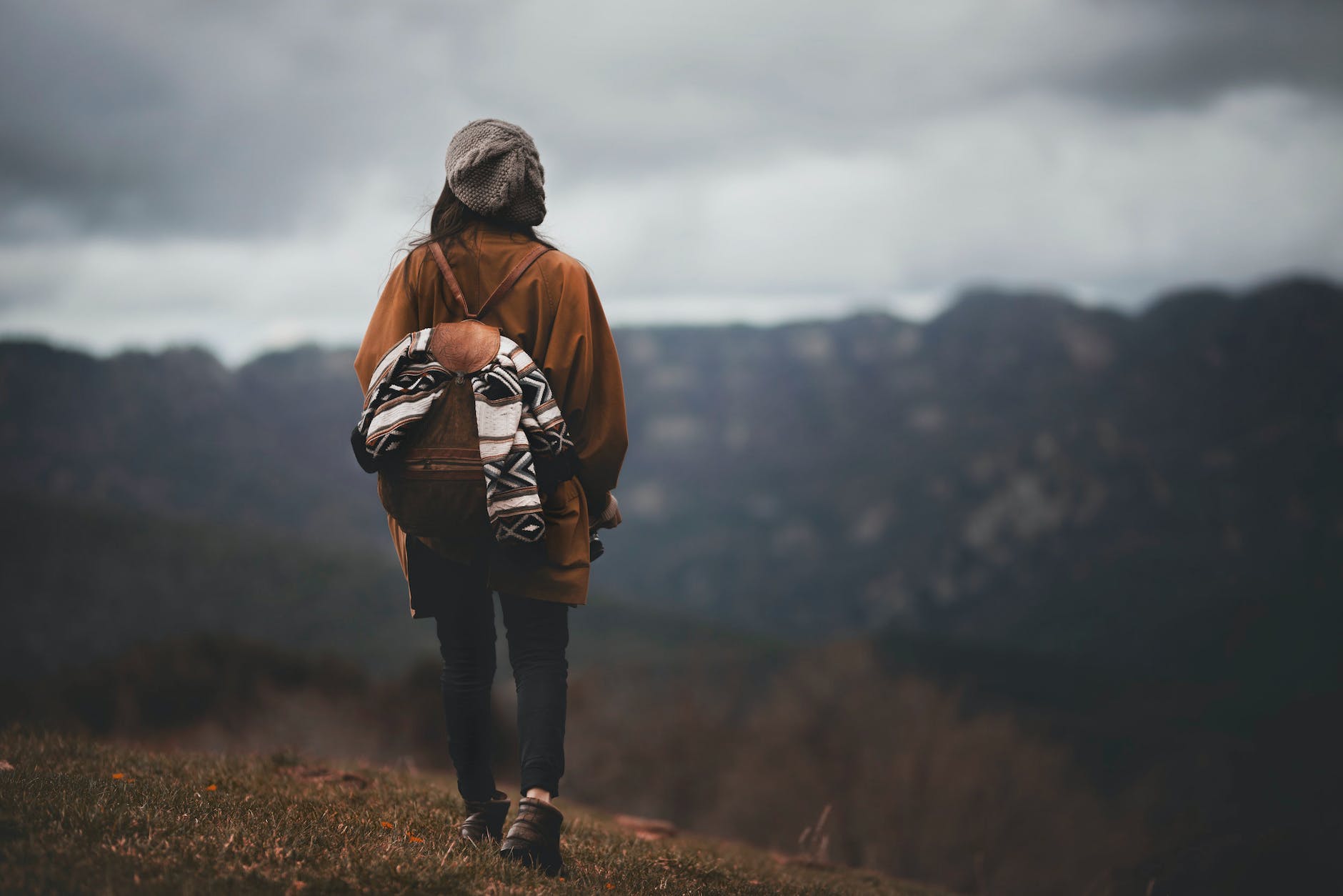 back view of a backpacker walking on a grass field