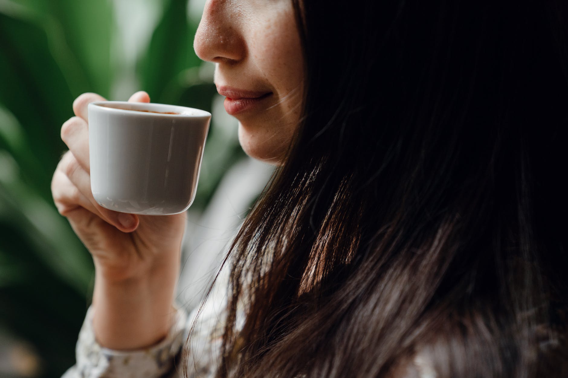 crop female enjoying fresh aromatic coffee from little cup