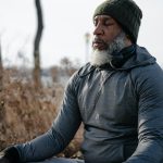 thoughtful black man in activewear meditating in autumn park