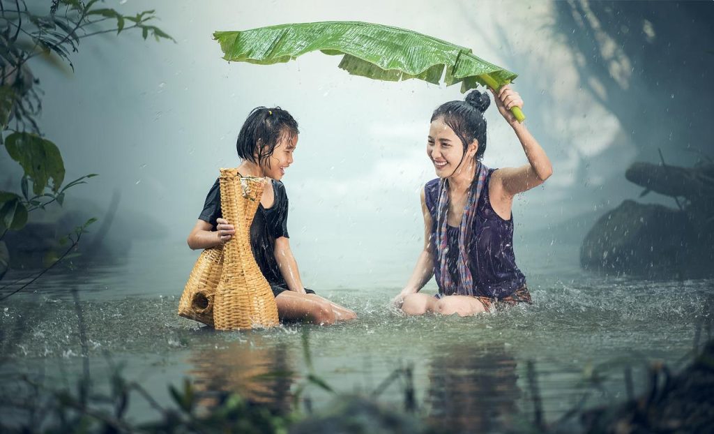 laughing women under banana leaf in the rainy season