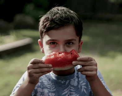 Barn som äter melon i trädgården