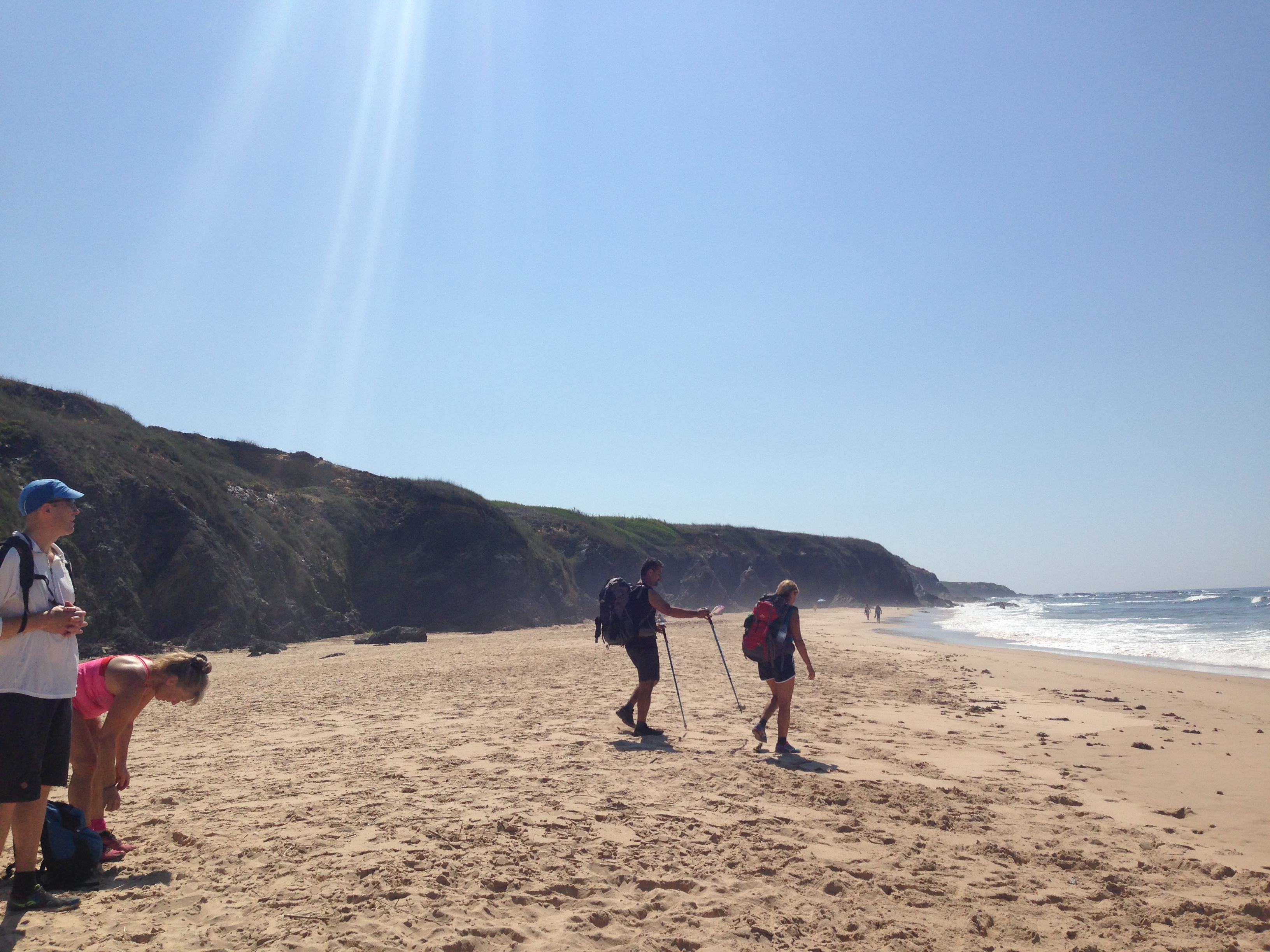 4 vandrare med ryggsäck har stannat till på en stor strand för att ta sig ett dopp
