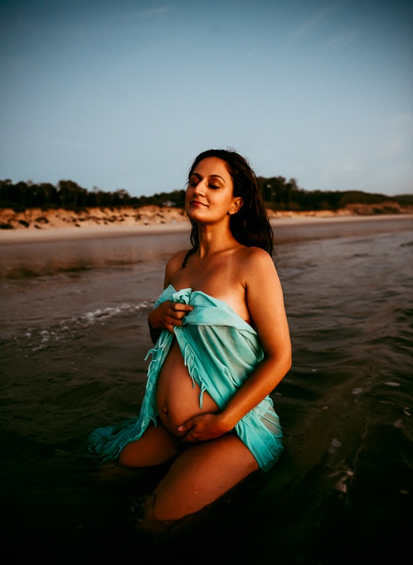 Pregnant woman sitting in the sea for West Sussex maternity photographer