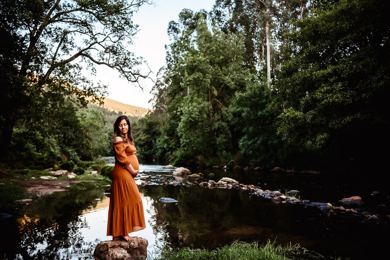 pregnant woman in front of a river during pregnancy session with vanessa gomes photography